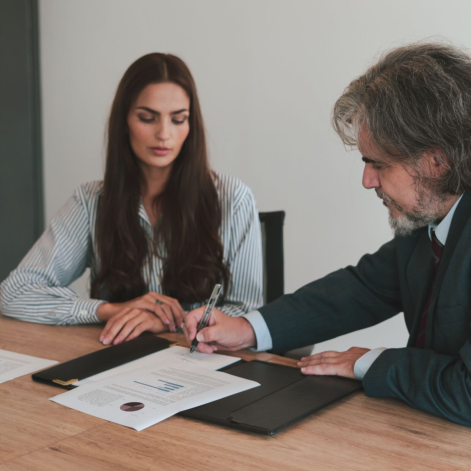 Professional business meeting with two colleagues reviewing documents at an office desk.