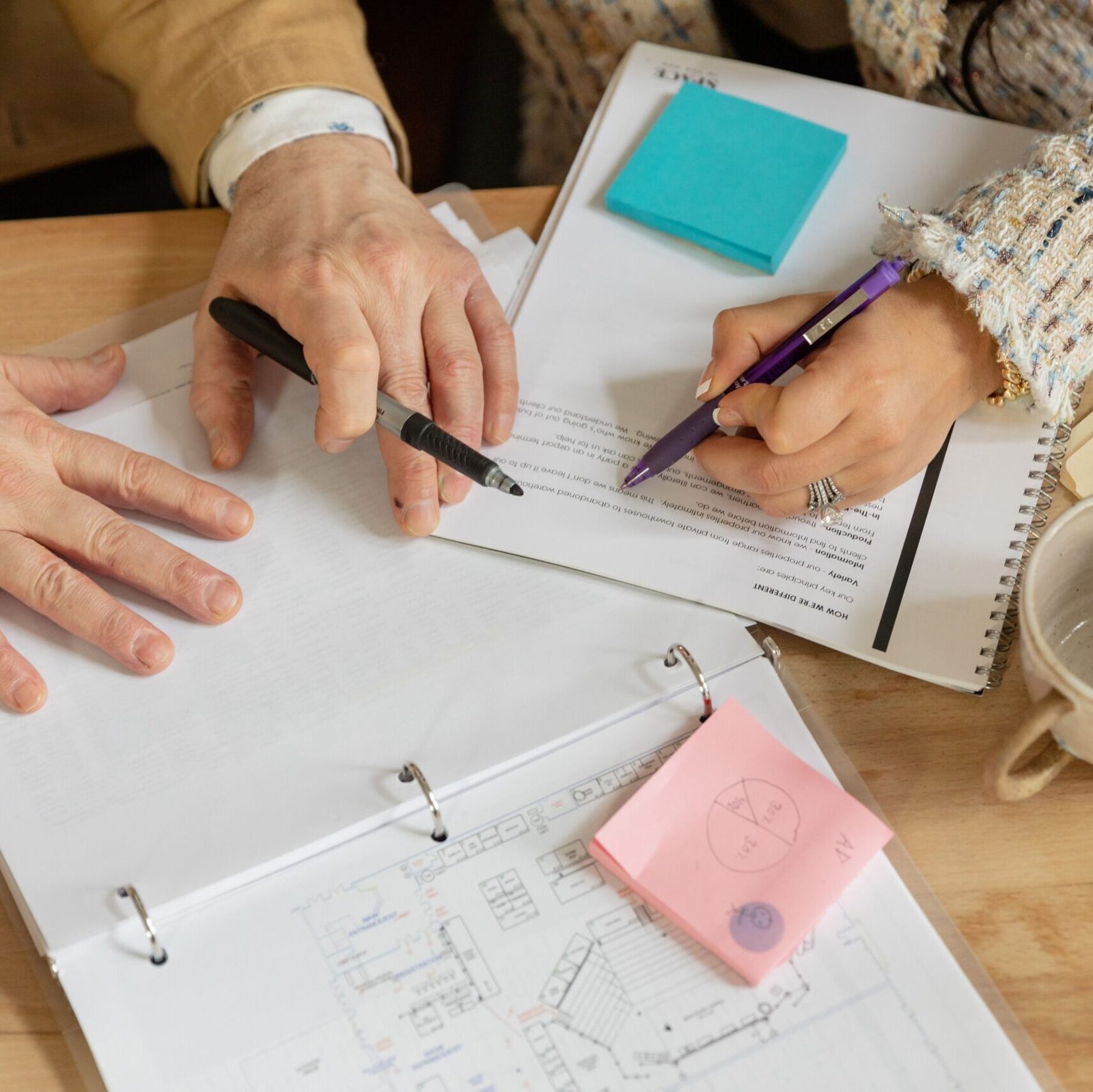 Close-up of two coworkers collaborating over documents and planning in an office setting.